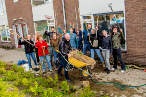 Groepsfoto van buurtbewoners die samen plantenvakken aanleggen