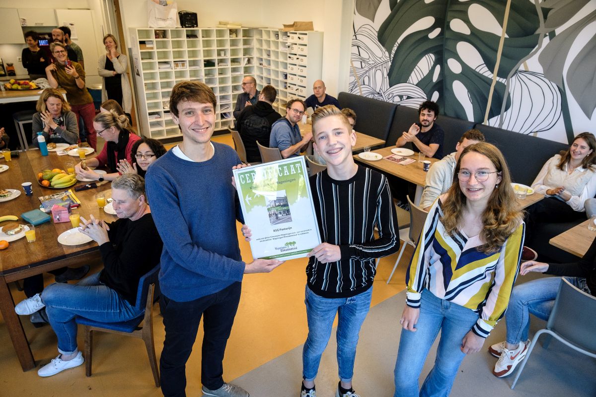 Leerling krijgt een certificaat uitgereikt van een beleidsmedewerker duurzaamheid van gemeente Wageningen