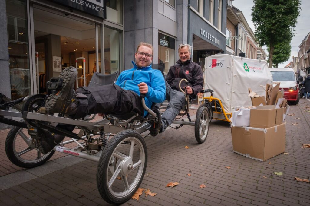 Twee mannen halen karton op met de fiets van het Afvalcollectief