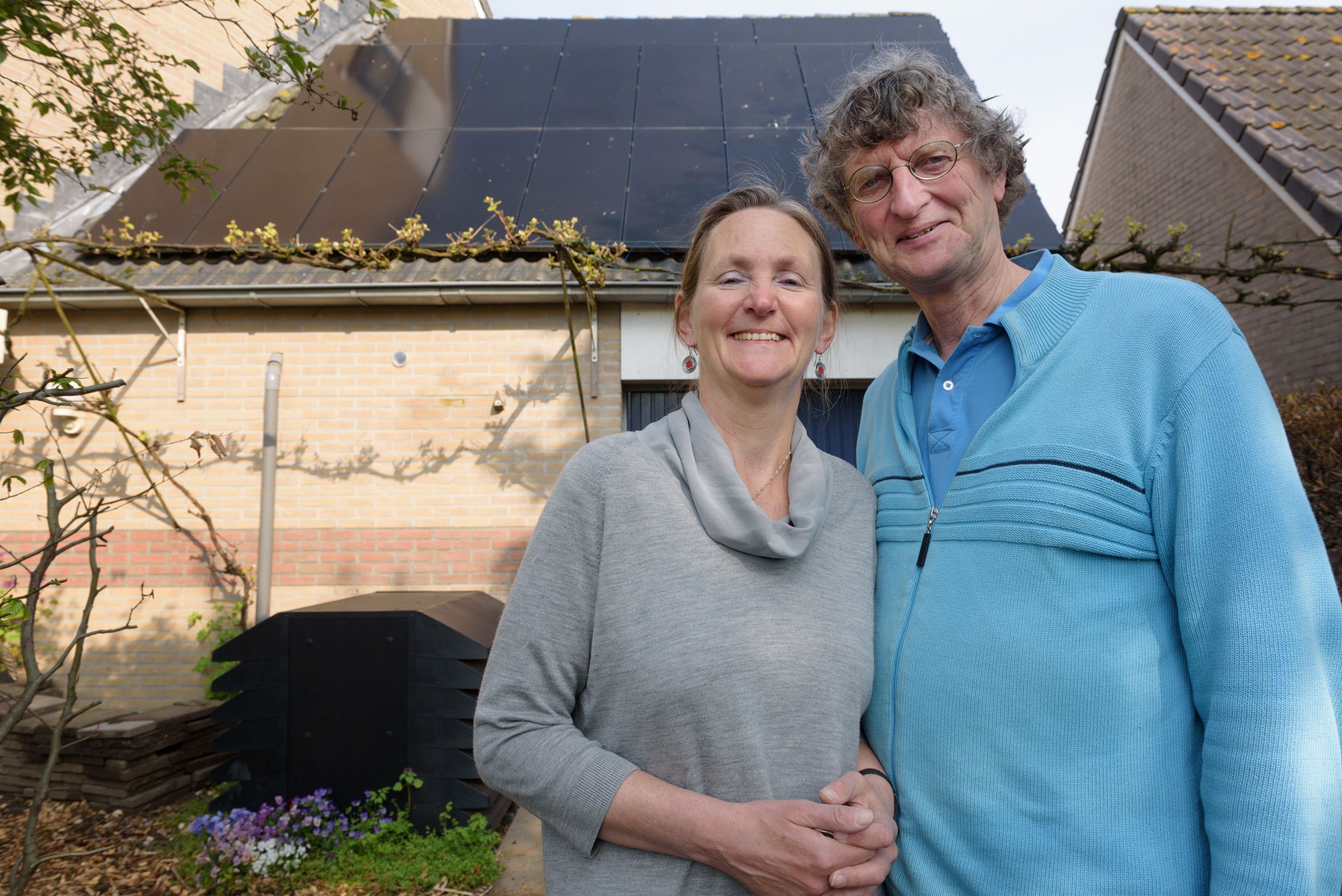 Man en vrouw voor huis met zonnepanelen op het dak