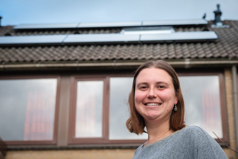 Vrouw voor huis met zonnepanelen op het dak