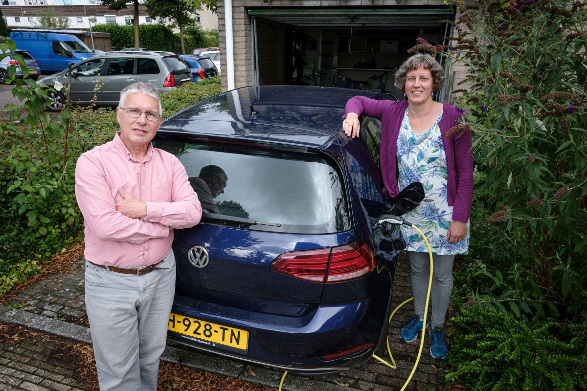 Man en vrouw staan naast elektrische auto aan stekker